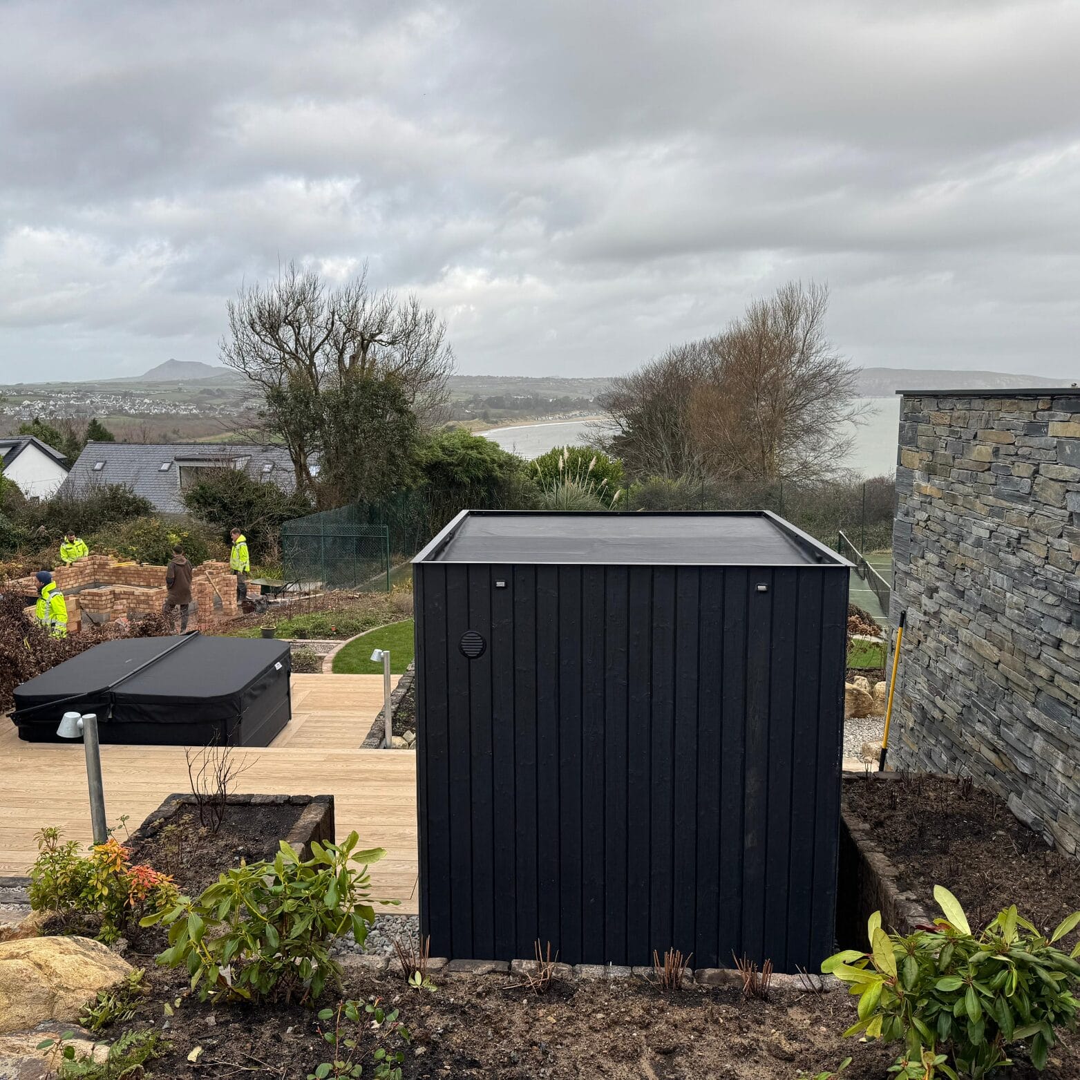 Outdoor cube shaped sauna with a sloping rubber roof.